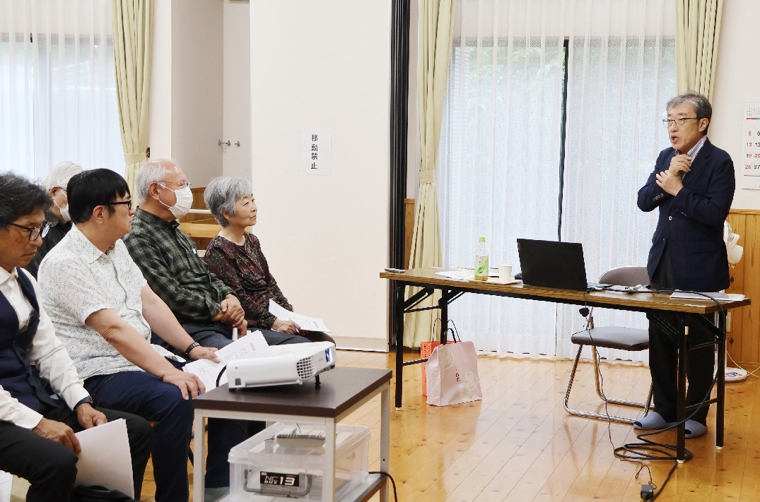 防空壕に刻まれた文字について、地域住民に報告する藤井通彦さん