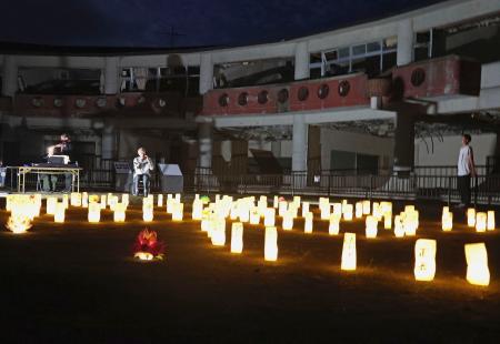 東日本大震災で被災した旧大川小で、犠牲者に思いをはせ明かりがともされた紙灯籠＝１５日夕、宮城県石巻市