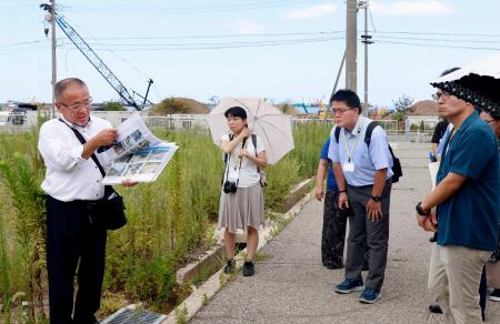 朝市通り周辺で橋爪朱文さん（左端）から説明を聞く学校関係者ら＝１８日午後、石川県輪島市