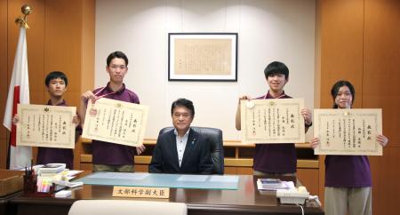 文科省の小林茂樹副大臣（中央）を表敬訪問した（左から）天河龍佑さん、東城陸大さん、（１人おいて）宇宿光琉さん、内田菜緒さん＝１８日午後