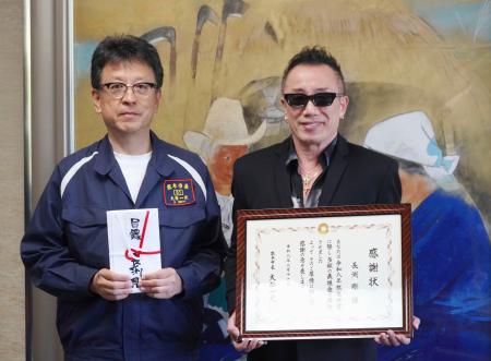 熊本市の大西一史市長（左）を表敬訪問し、義援金として市に１千万円を寄付した歌手長渕剛さん＝１９日午前、熊本市役所