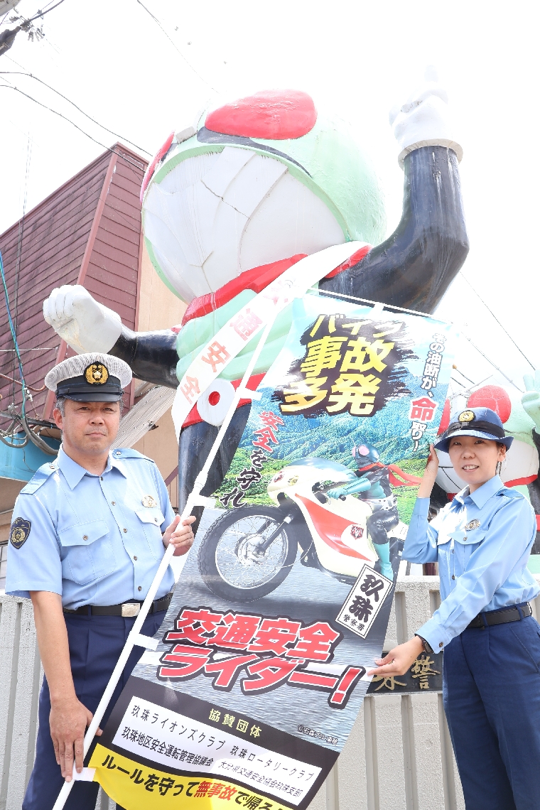 バイク事故防止を呼びかける仮面ライダーののぼり旗。奥は仮面ライダー像＝玖珠署