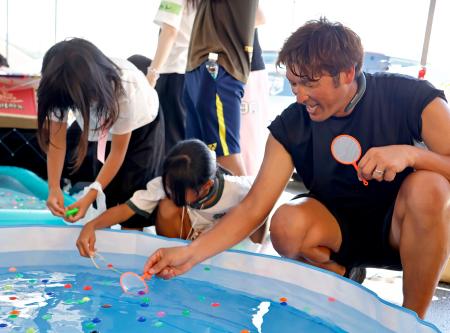 熊本県宇城市の小川防災拠点センターで子どもたちと交流するサッカー元日本代表の巻誠一郎さん（右）＝２５日午前