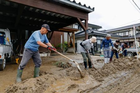 石川県羽咋市で住宅に流れ込んだ泥を道路に出す人たち＝２８日午前
