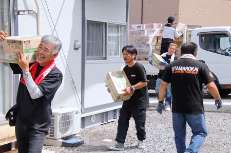 入居が始まった仮設住宅に支援物資を運び込む有志のトラック運転手ら＝５日午前、熊本県氷川町