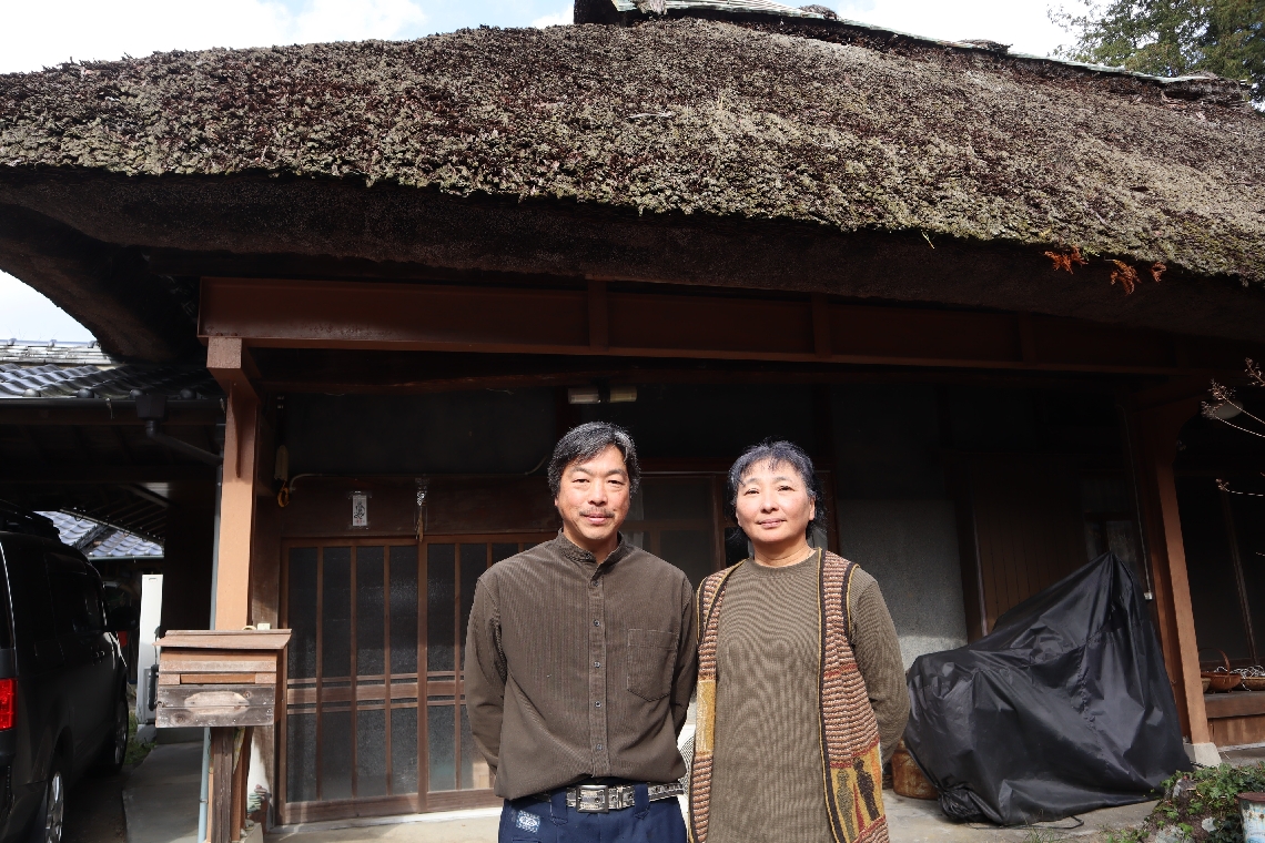 上村明子さん（右）と上村組の棟梁で夫の淳さん（左）が暮らす茅葺き屋根の家＝日田市前津江町、２０２５年１２月