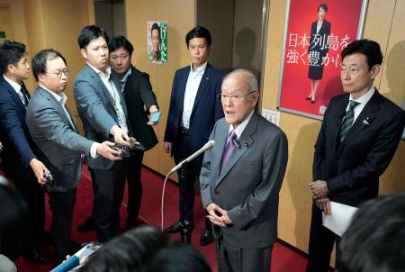 沖縄県知事選で古謝玄太氏の当選が決まり、記者団の取材に応じる自民党の鈴木幹事長。右端は西村選対委員長＝１３日夜、東京・永田町の党本部