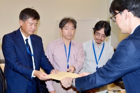 内閣府の担当者に提言を手渡す東北学院大の郭基煥教授（左端）＝１８日午後、国会
