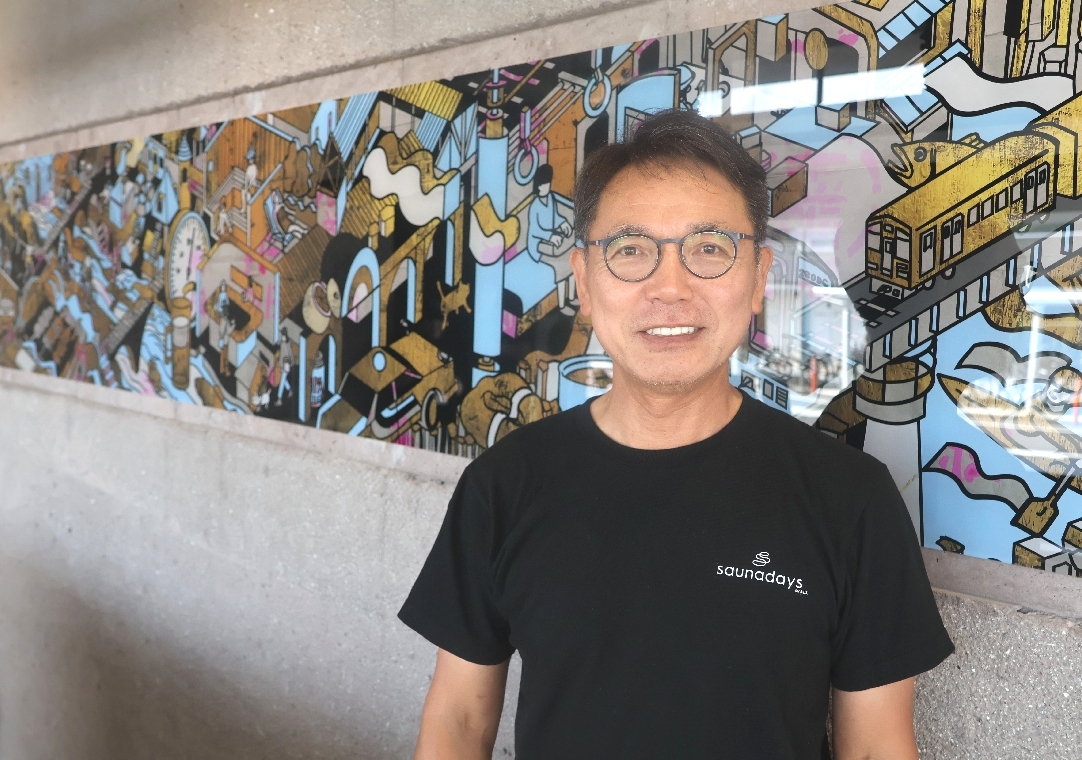 豊後大野市が詰まった「私たちの、好きなまち」の前で笑顔の中村社長＝豊後大野市三重町