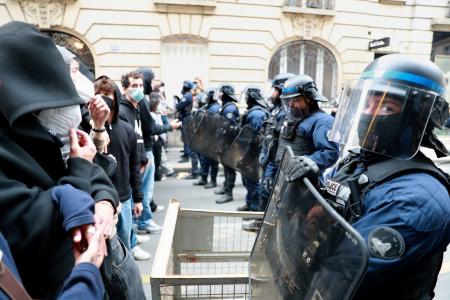 ７日、パリ政治学院の前で向かい合うデモ隊と警官隊（共同）