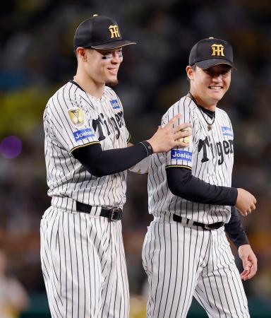 今季最終戦のセレモニーを終え、笑顔で引き揚げるプロ野球阪神の佐藤輝明内野手（左）。４年ぶり９人目の三冠王に輝いた＝８日、甲子園球場