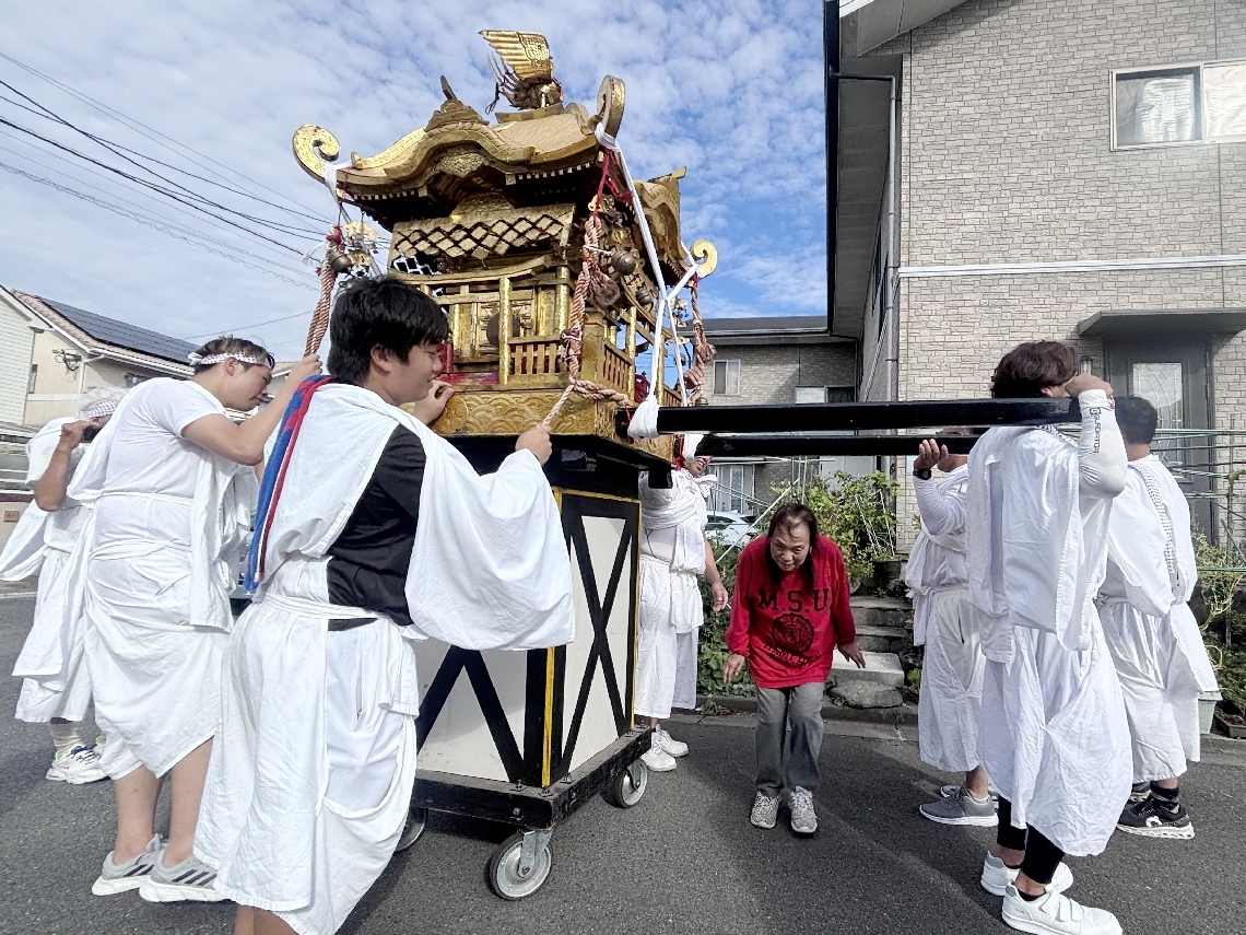 台に乗せられたみこしの下をくぐる住民＝１１日午後３時、大分市坂ノ市中央