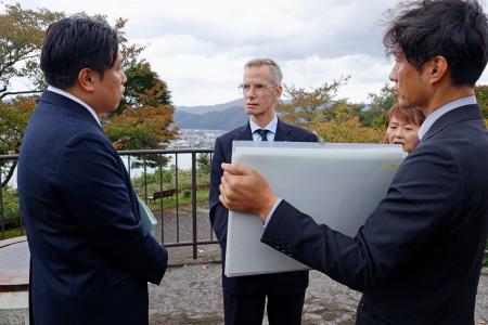 拉致現場付近で福井県警の担当者から説明を受けるジェローム・ライアン氏（左から２人目）＝２２日午前、福井県小浜市