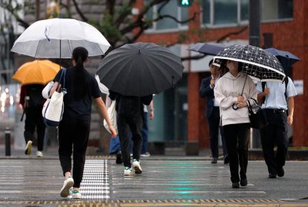 傘を差してＪＲ熊本駅前の横断歩道を渡る人たち＝２６日午前、熊本市