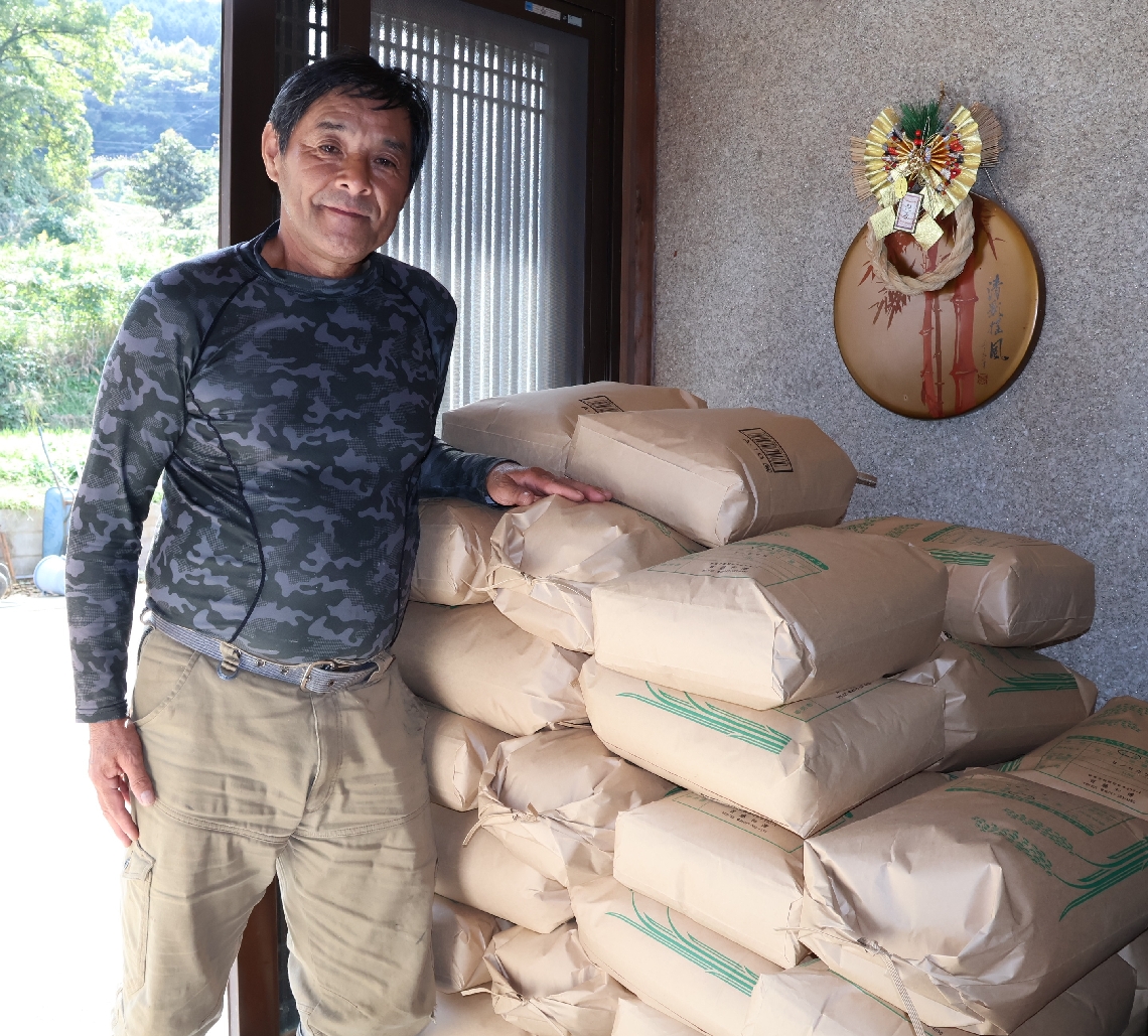 祭りで販売するコメを手にする首藤和博区長＝２９日、由布市挾間町朴木